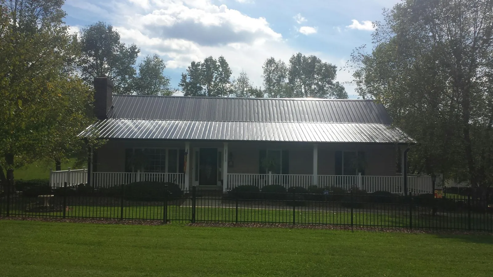 Gray metal roof on a brick ranch with a full width front porch — Gutter Guard Installation work by our crew in Voorhees