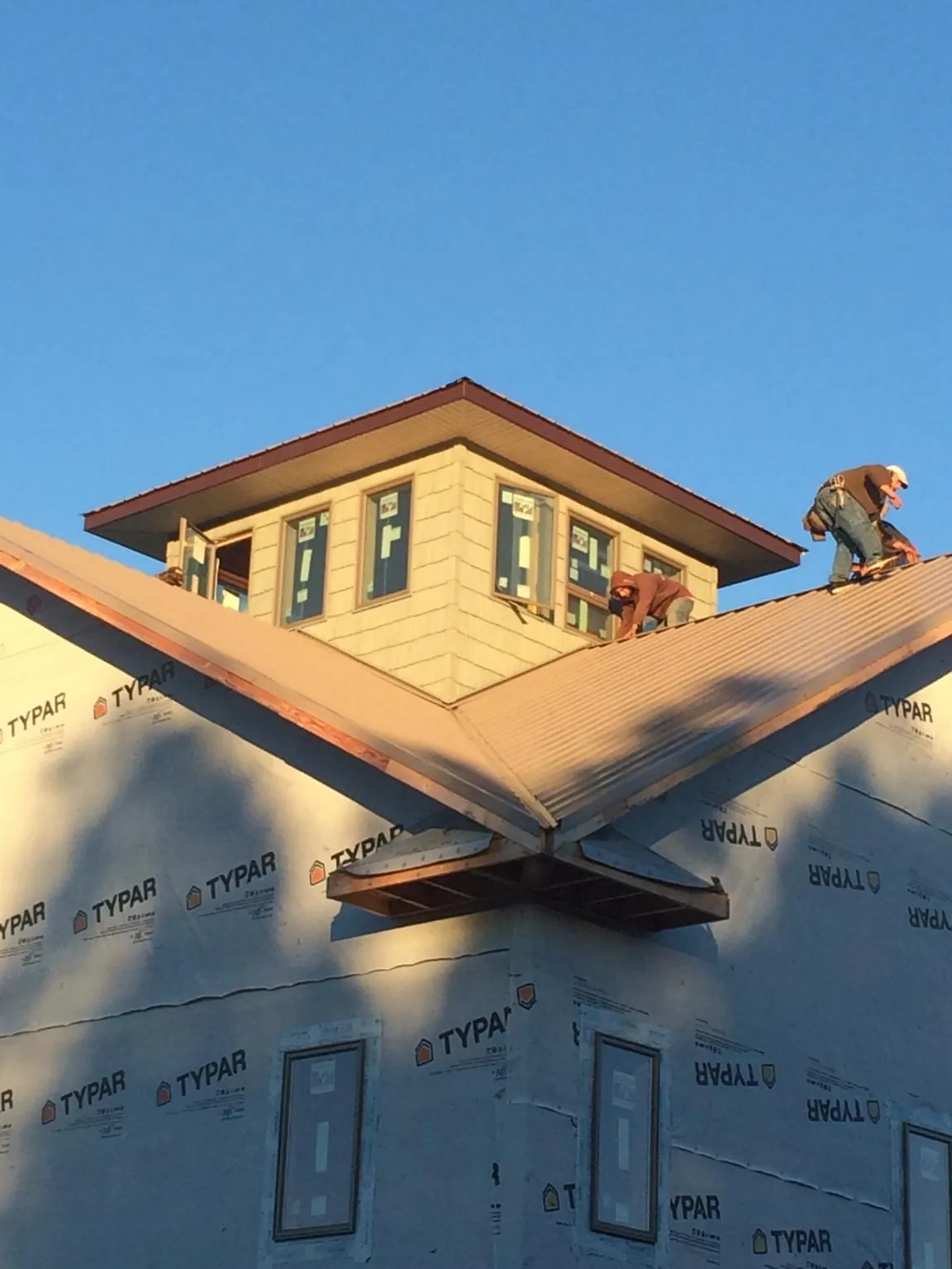 Roofers working around a rooftop cupola on a new metal roof at sunset — Roof Waterproofing in Voorhees by Roofing Brothers
